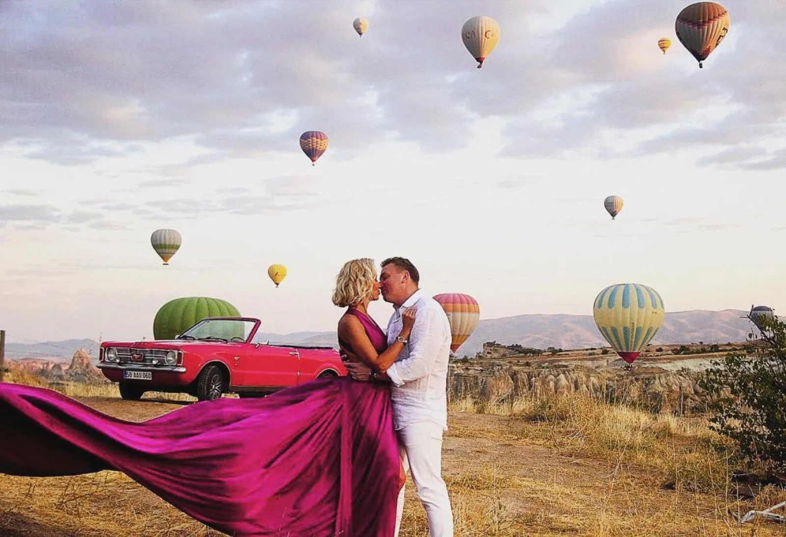 Couple at sunrise with dozens of balloons in the sky